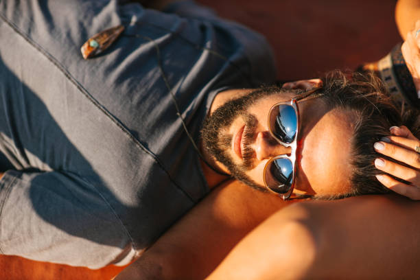 Closeup portrait of awesome tanned curly man in classic brown jacket trendy sunglasses posing isolated on beige pastel background. Fashion New Collection offer. Retro style concept. Free place for ad