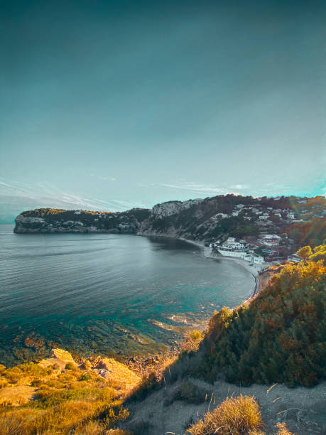 Stunning images of a rocky bay on the Spanish coast. The photos showcase majestic cliffs and the sparkling blue waters of the Mediterranean Sea under a clear sky. Perfect for travel photography, nature images, and landscape shots