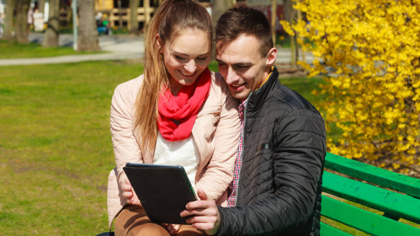 istock couple with tablet sitting on bench outdoor 2155060831