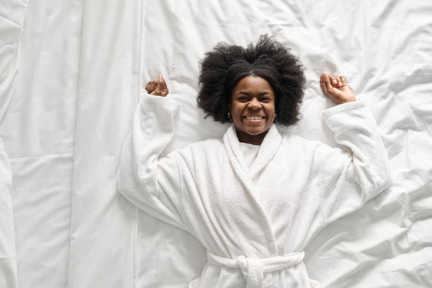 Young Black woman lying on bed and smiling