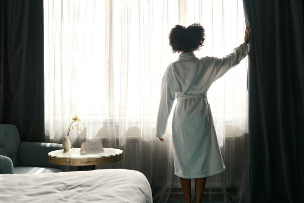 istock Woman wearing bathrobe opening curtains 2155061899