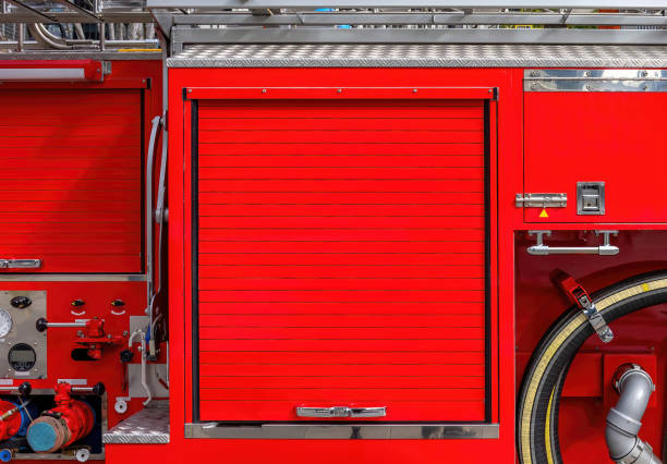istock Side view of a red fire engine with a closed roller door for copy space. Background motif for flyers on the subject of fire brigades. 2155063466