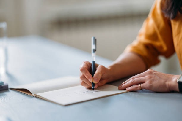 Person Writing In Notebook At A Light Blue Desk