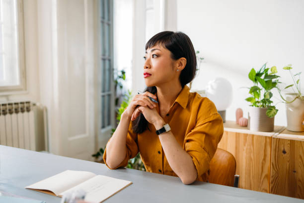 istock Thoughtful Woman Sitting at Table in Bright Room 2155064719
