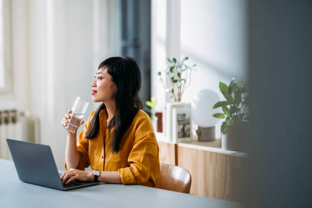 istock Woman Working Remotely Enjoying a Drink in Home Office 2155064732