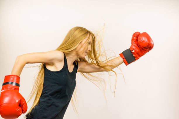 Blonde long hair woman in big red gloves boxing. Female fight for equal rights for women. Side view. Gender equality concept.