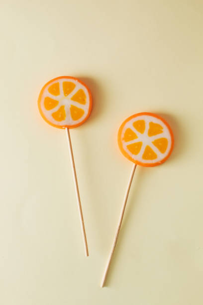 istock Two orange lollipops on beige background. Minimal concept idea 2155069347