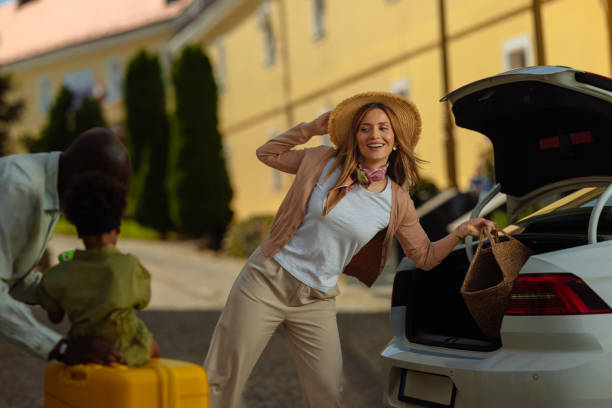 istock Cheerful woman unloading luggage from car trunk 2155074740