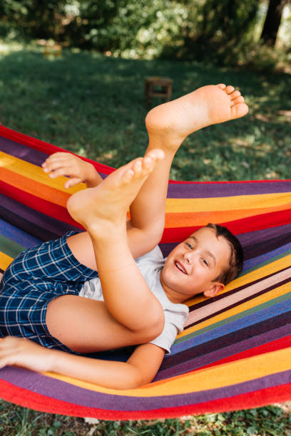 Boy enjoys summer resting and lying in a hammock in the yard