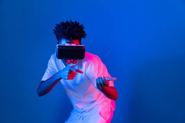 istock Young African American player using VR turn hunter game neon wall. Contrivance. 2155078613