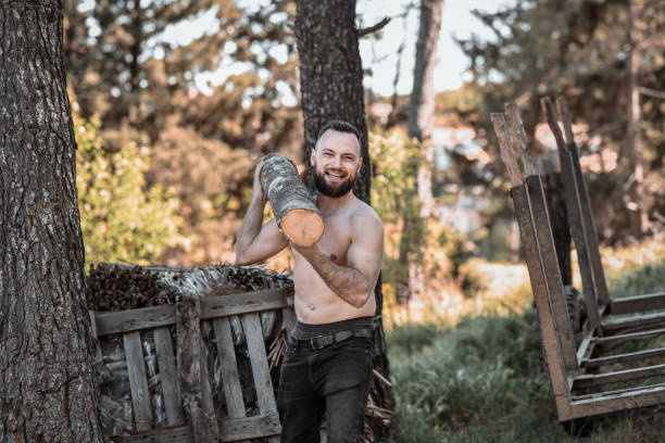 Smiling Male Working With Firewood Logs In Forest