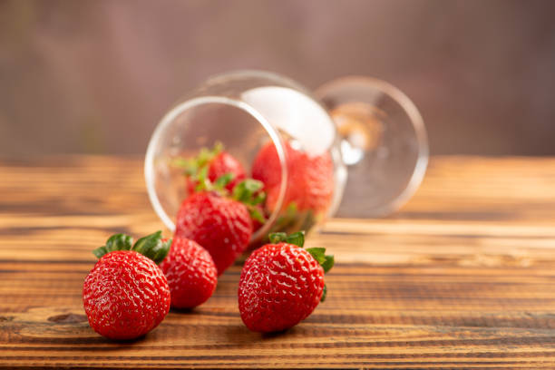 Beautiful crystal glass with strawberries on rustic wood, selective focus.