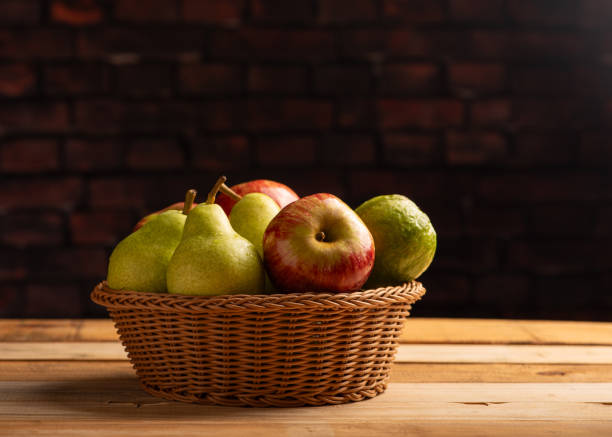 Basket with fruits on rustic wooden surface and dark background, selective focus.