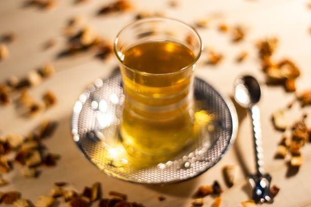 traditional turkish cup of apple black tea with silver plate and spoon and scattered pieces of tea with shallow depth of field