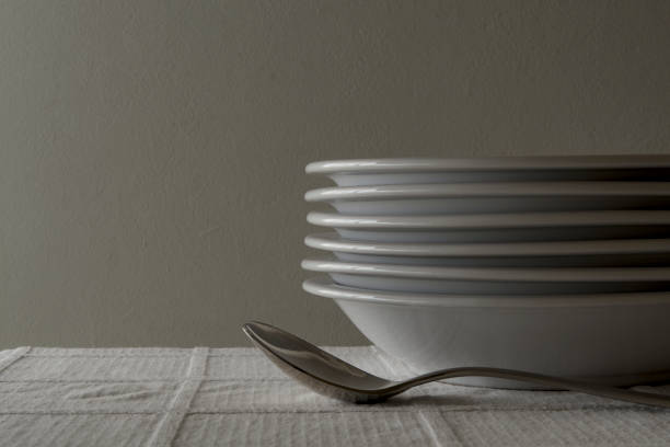 istock Spoons and soup plates stacked on a white tablecloth 2155081409