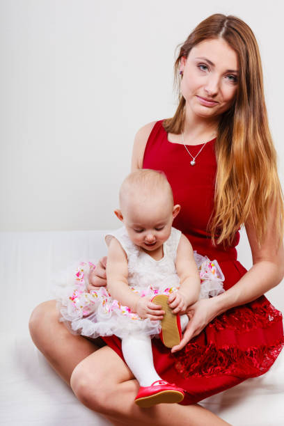 Single parent concept. Young elegant mother with baby girl in princess ballerina dress on mommy knees. Parenthood.