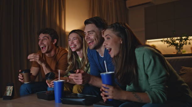 istock Joyful buddies enjoy tv show with drinks snacks at home evening close up. 2155082601