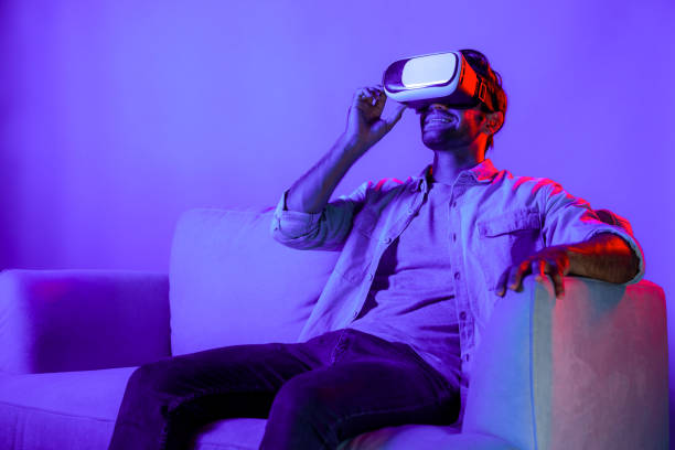 istock Happy man looking at VR glass and sitting at sofa with neon light. Deviation. 2155082721
