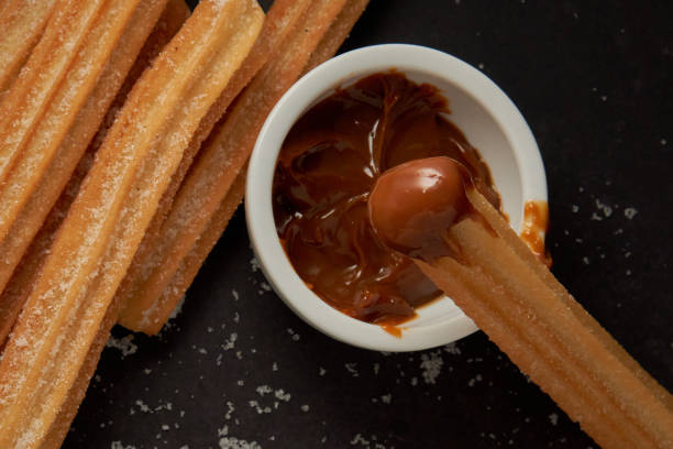 istock Churro with dulce de leche on the tip and more churros on a black background 2155087475
