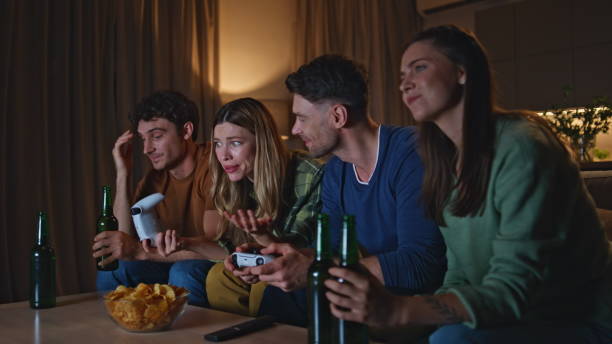 istock Friendly gamers playing videogame at evening home. Happy friends using consoles 2155088361