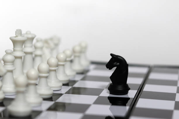 istock On a chessboard, a black horse encounters a white chess enemy. 2155094880