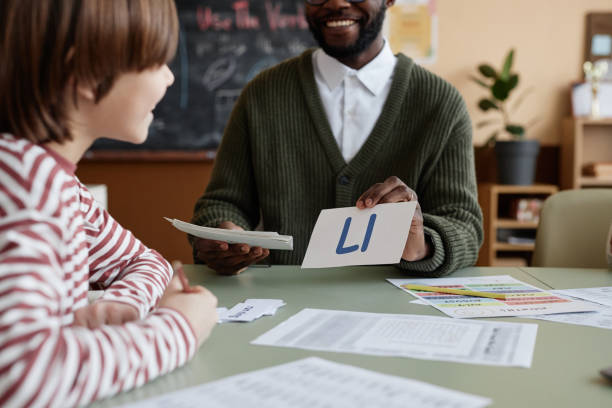 Cheerful Teacher Showing Letter Card To Boy
