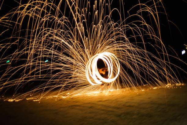 istock asian man swinging fire on the beach at night 2155097417