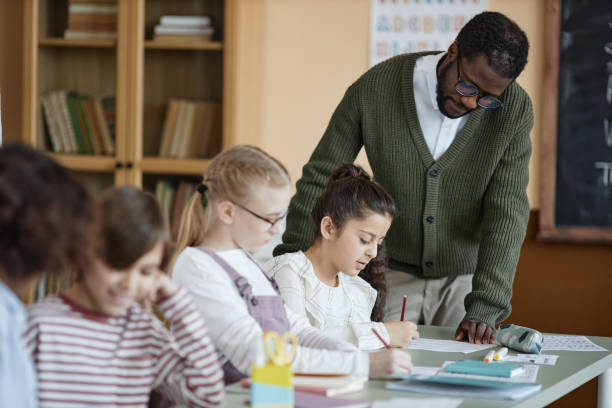 istock Teacher Helping Girl With Task In Class 2155102226