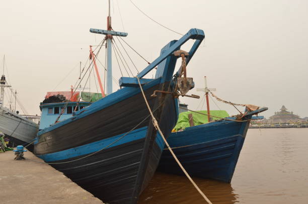 a blue wooden boat with a black tarp on the side is docked on river port