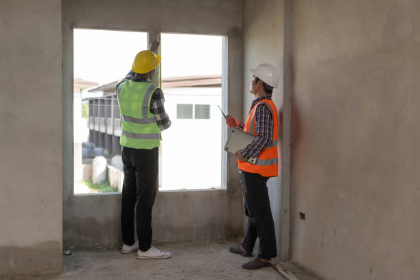 istock Foreman, engineer or architect wearing hard hat holds laptop and blueprints to check details about real estate construction in Construction area of ​​an unfinished building 2155112177