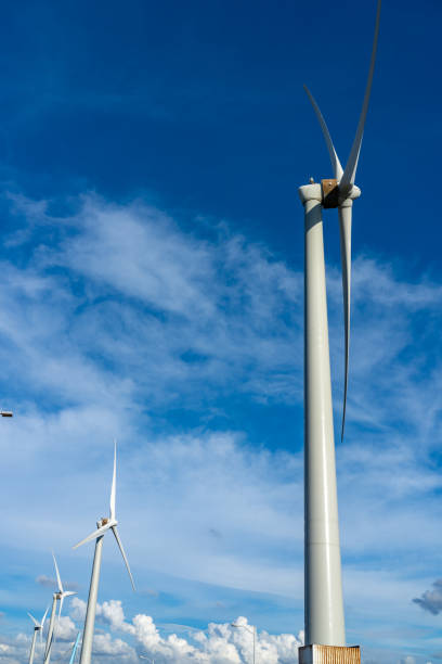 Close-up wind turbines or wind energy converter in sunny day with blue sky and white clouds