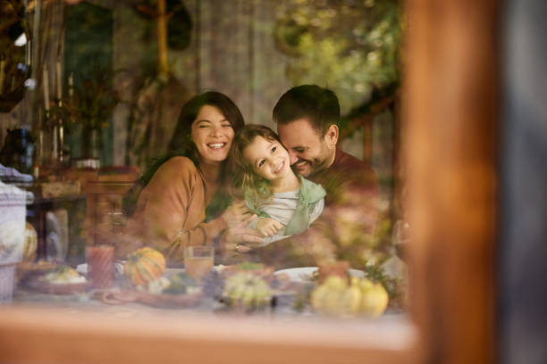 istock Happy parents enjoying with their daughter at dining table. 2155115018