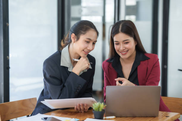 istock Two asian businesswomen discussing and reviewing documents in office. Professional workplace consultation. Corporate business and teamwork concept. 2155116568