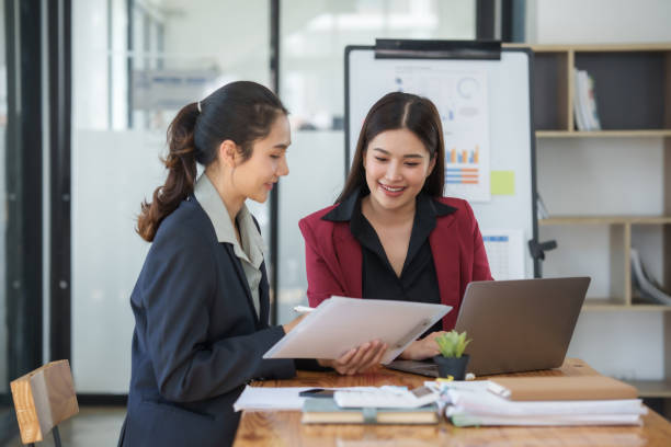 istock Two asian businesswomen discussing and reviewing documents in office. Professional workplace consultation. Corporate business and teamwork concept. 2155116569