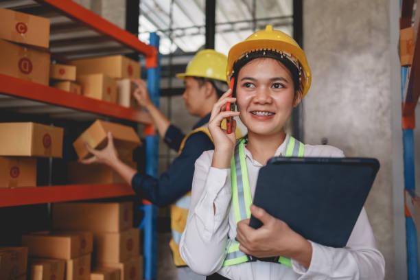 istock Asian female supervisor using mobile phone to chat with customers and check inventory with tablet to check product quality. 2155116722