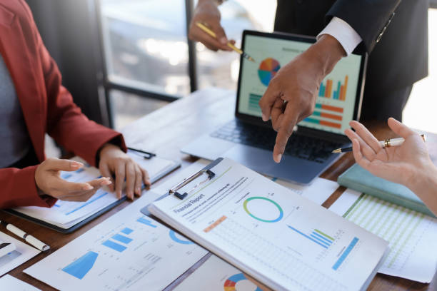 istock A group of business professionals engaged in analyzing financial reports and data on a laptop in a meeting. 2155117307