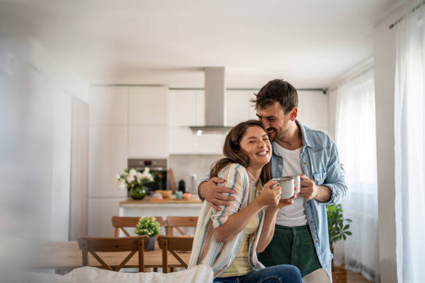 young couple drinking morning coffee enjoying the weekend in their new apartment - người sở hữu nhà bức ảnh hình ảnh sẵn có, bức ảnh & hình ảnh trả phí bản quyền một lần