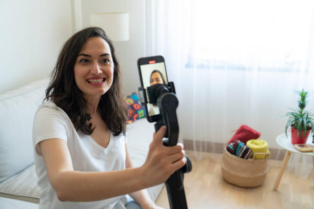 istock Woman using mobile phone recording video live streaming online at home 2155121979