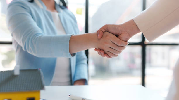 istock Real estate agent shakes hands with a client to sign a home purchase contract congratulating the client on the purchase. 2155122321