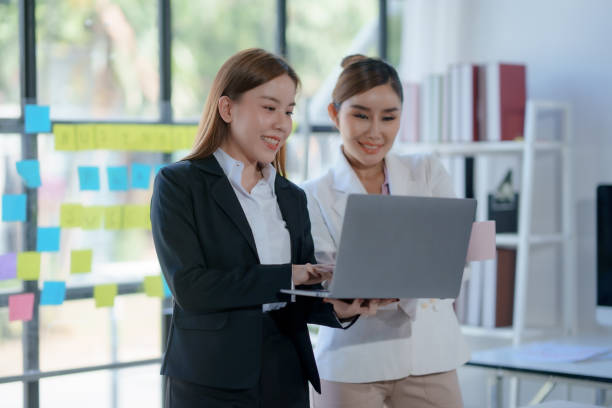 istock Two happy asian businesswoman talking and using a laptop computer in a meeting. 2155122587