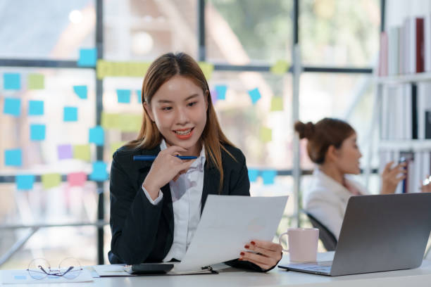 istock Young Asian businesswoman working document and project in modern office. Financier working with documents at workplace. 2155122610