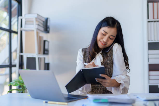 istock Professional asian business woman sitting working and talking on the phone while with a laptop in the office. 2155123201