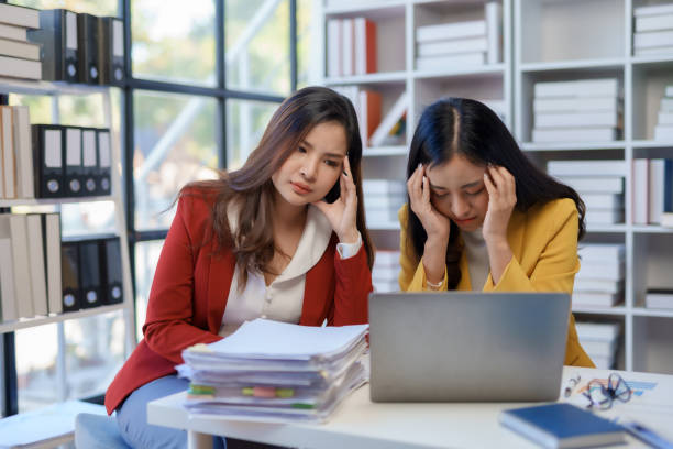 istock Two asian business woman stressed over financial documents. Corporate strategy and problem-solving concept 2155123235