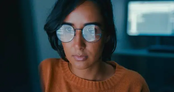 Photo of Female computer programmer works on complex software development tasks at her home office late into the night. Software developer, artificial intelligence and programming.