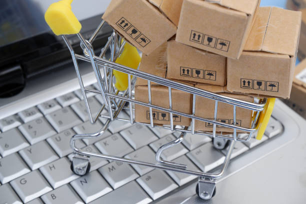istock Shopping cart, and shipping carton boxes on laptop computer keyboard. 2155124103