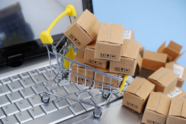 istock Shopping cart, and shipping carton boxes on laptop computer keyboard. 2155124121
