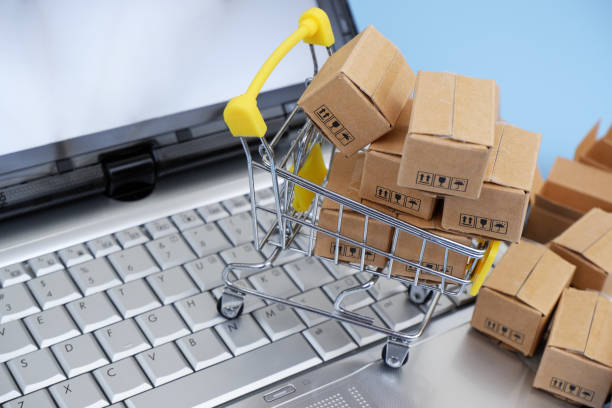 istock Shopping cart, and shipping carton boxes on laptop computer keyboard. 2155124123