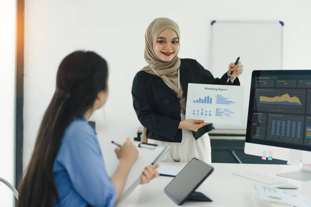 istock Two colleagues discuss marketing report in modern office meeting. 2155125377