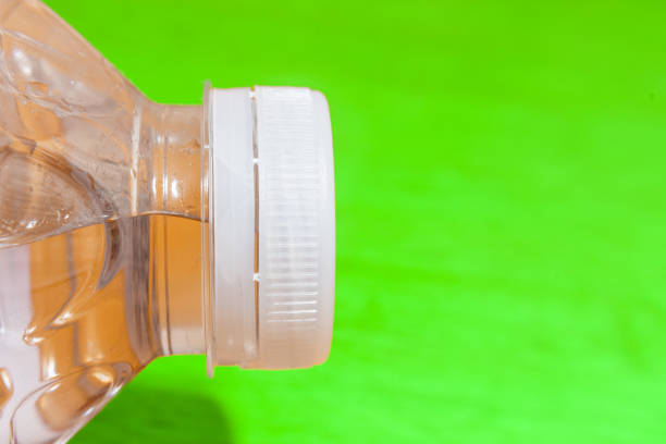 A plastic bottle, water and a plastic stopper closeup, macro shot. Green surface.