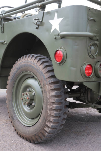 United States Army Second World War Jeep Tyre close up Featuring 4 wheel drive, a 4 speed transmission and quite simple design, the Willys Jeep was a mass produced off roading vehicle perfect for military use. This view of the rear quarter side shows the the pressed metal body panels and rugged off road tyres. Underneath if looking closely its possible to see the leaf style suspension and rear drive axle of the Jeep.
This image was taken at an outdoor event over the weekend of 25th June 2023, where reenactors, living historians, and members of the public can come to experience what life was like during the second world war, with live demonstrations, battle reenactments, and static displays from all over the world. jeep 4x4 off road vehicle world war ii stock pictures, royalty-free photos & images